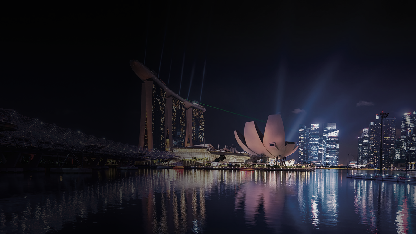 The Singapore skyline at night, lights reflecting on the water